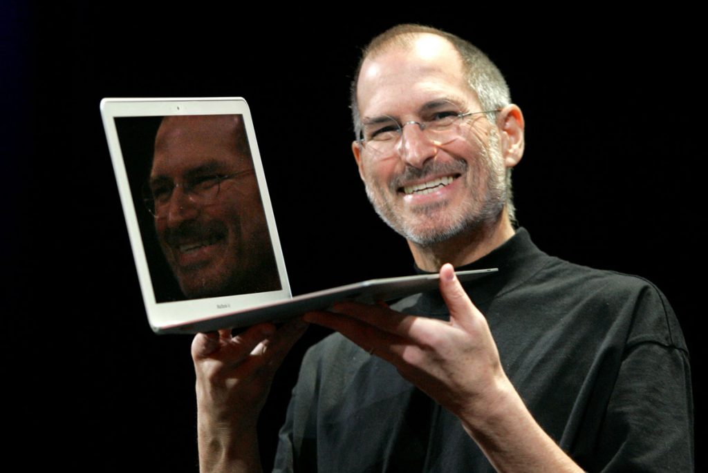 steve jobs tinand un laptop in maini